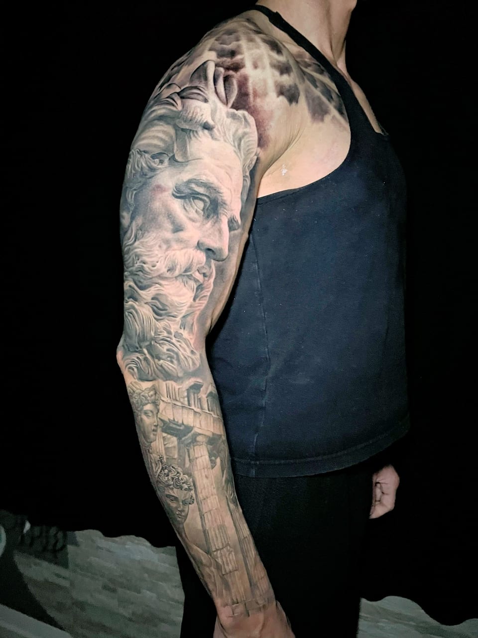 A black and grey realism sleeve combines bearded statues, columns and ornamental shapes.