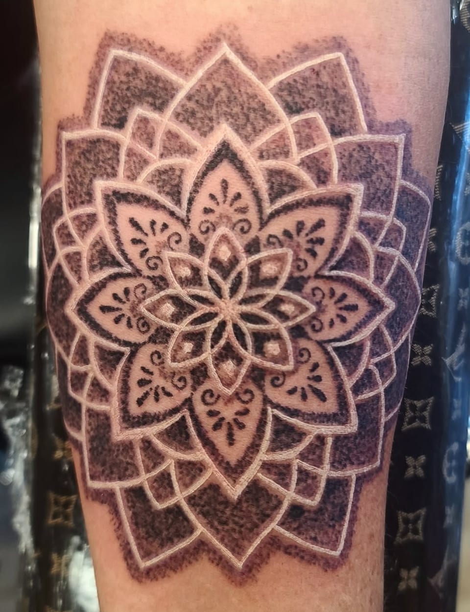 A black mandala tattoo uses pale petal outlines and dense dot shading.